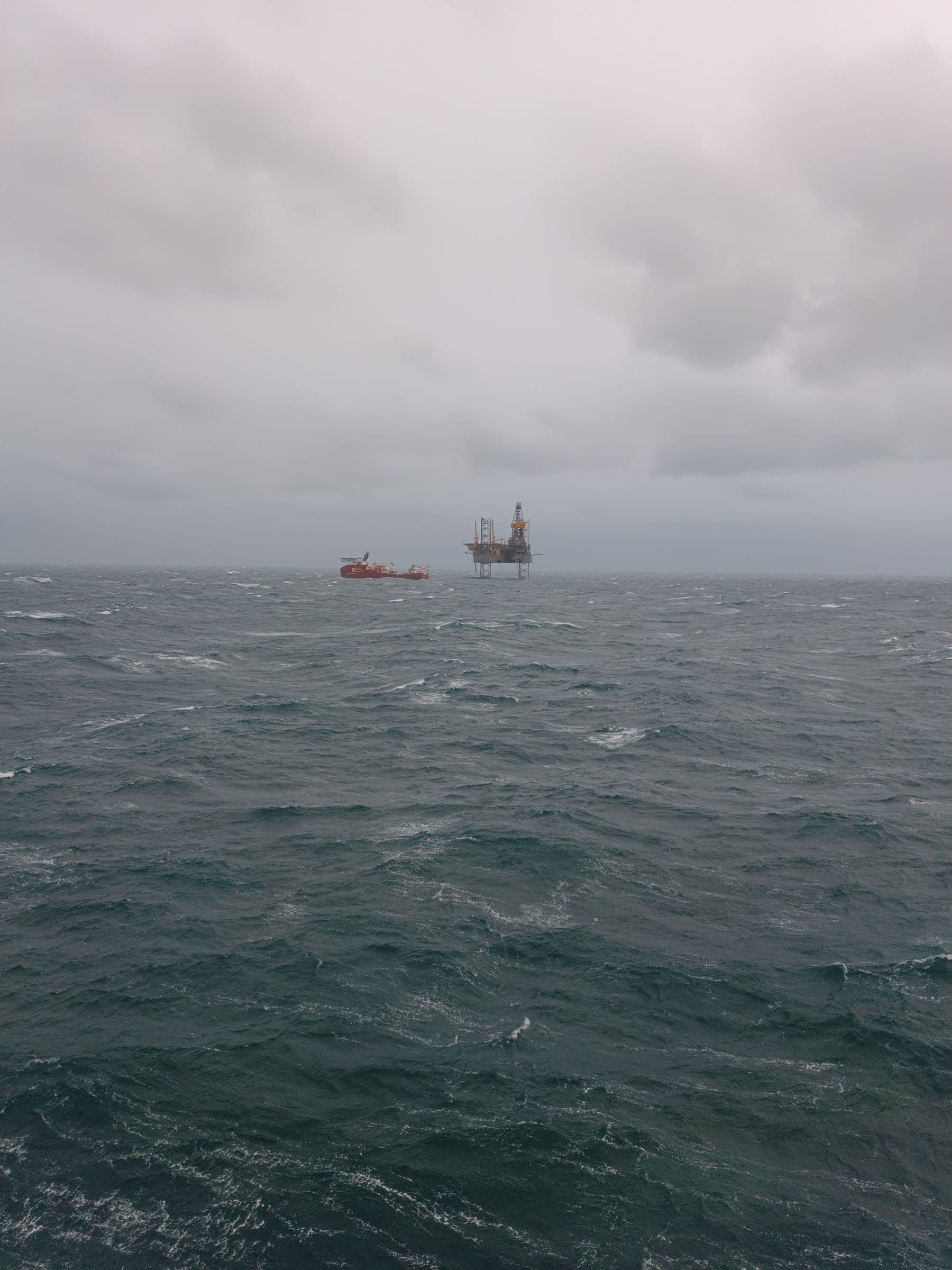 Offshore rig and support vessel working in heavy seas under cloud