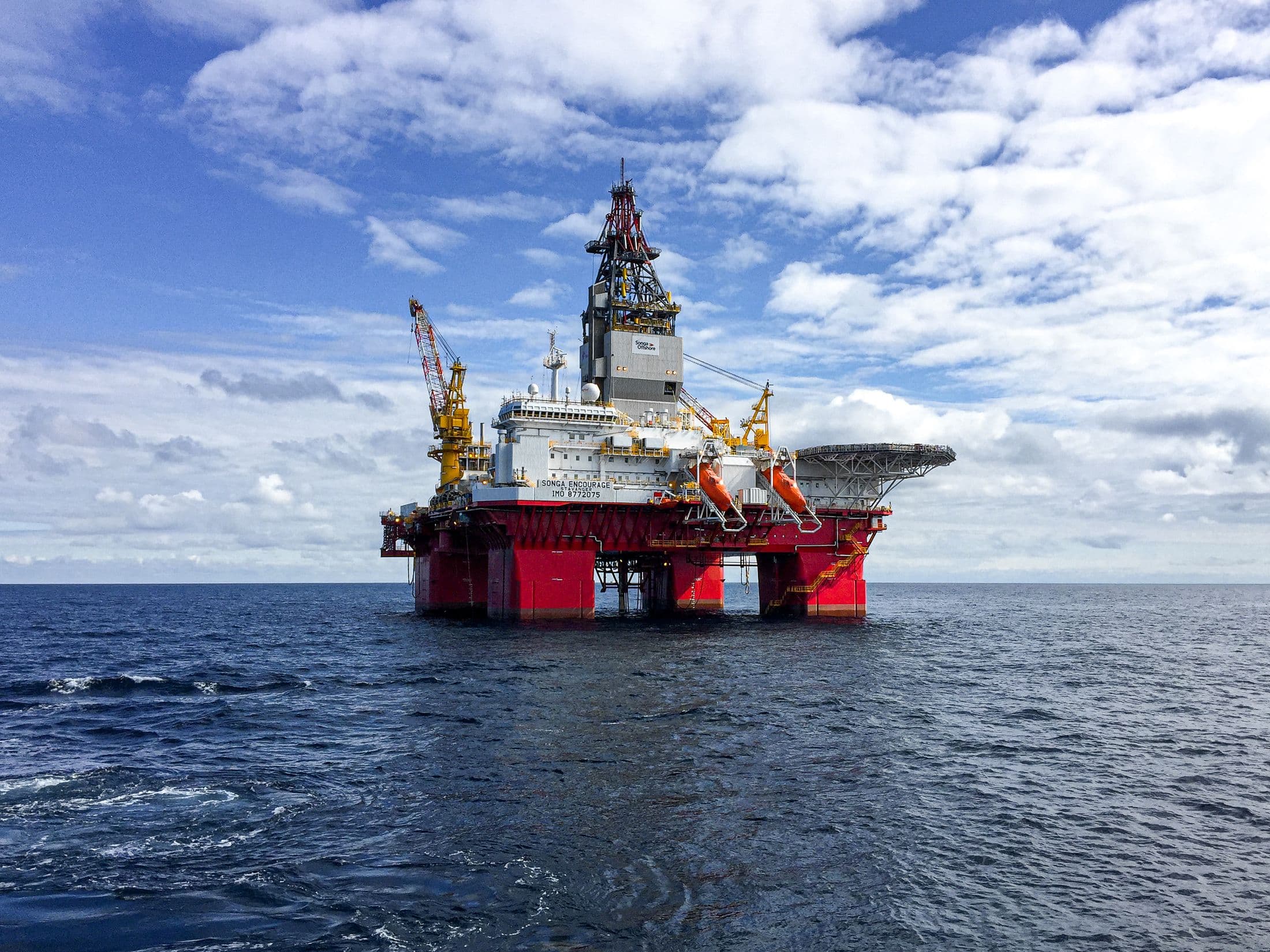 Semi-submersible drilling rig on open water under a partly clouded sky