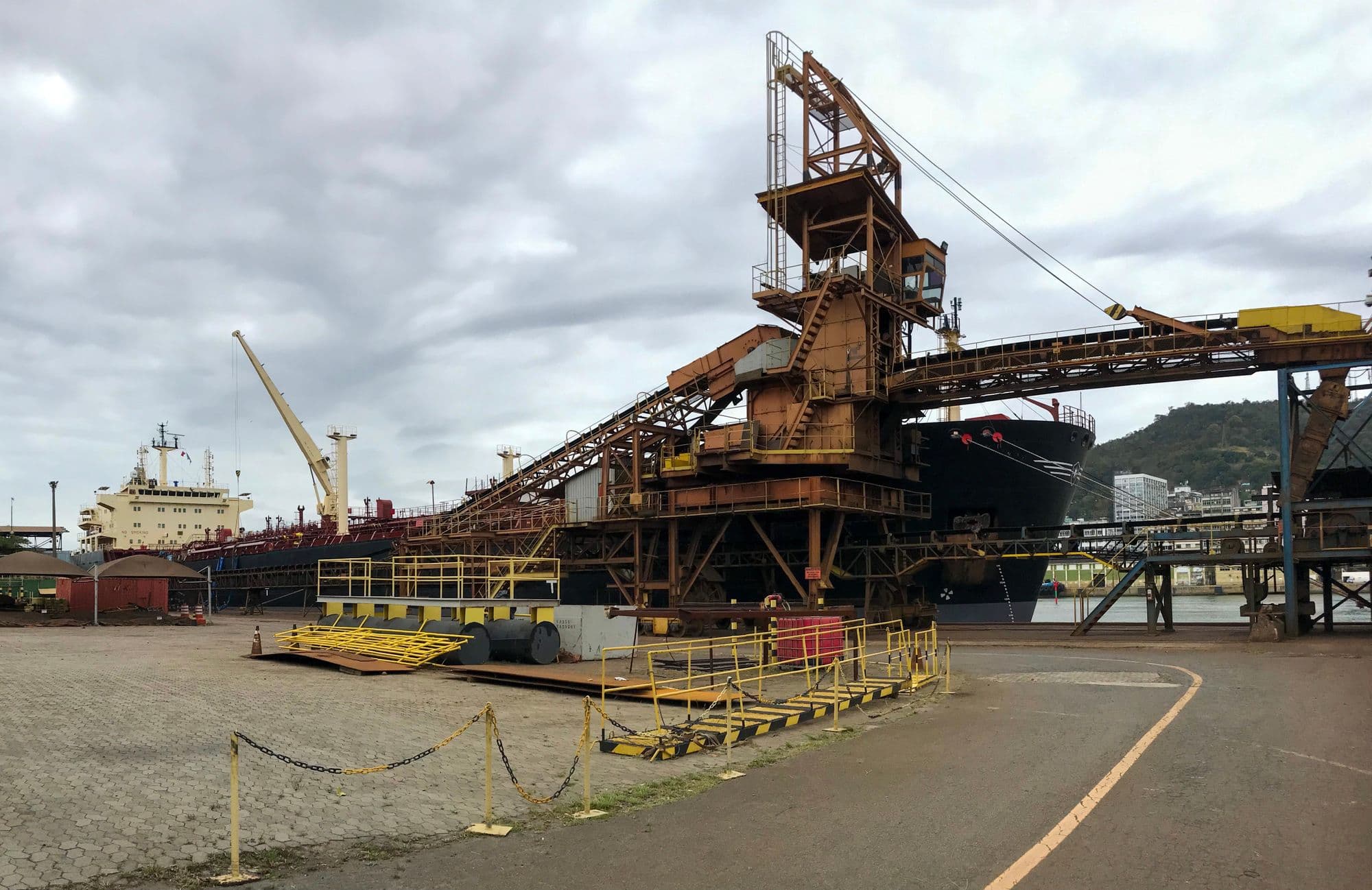 Cranes and vessels working at an industrial port under cloud