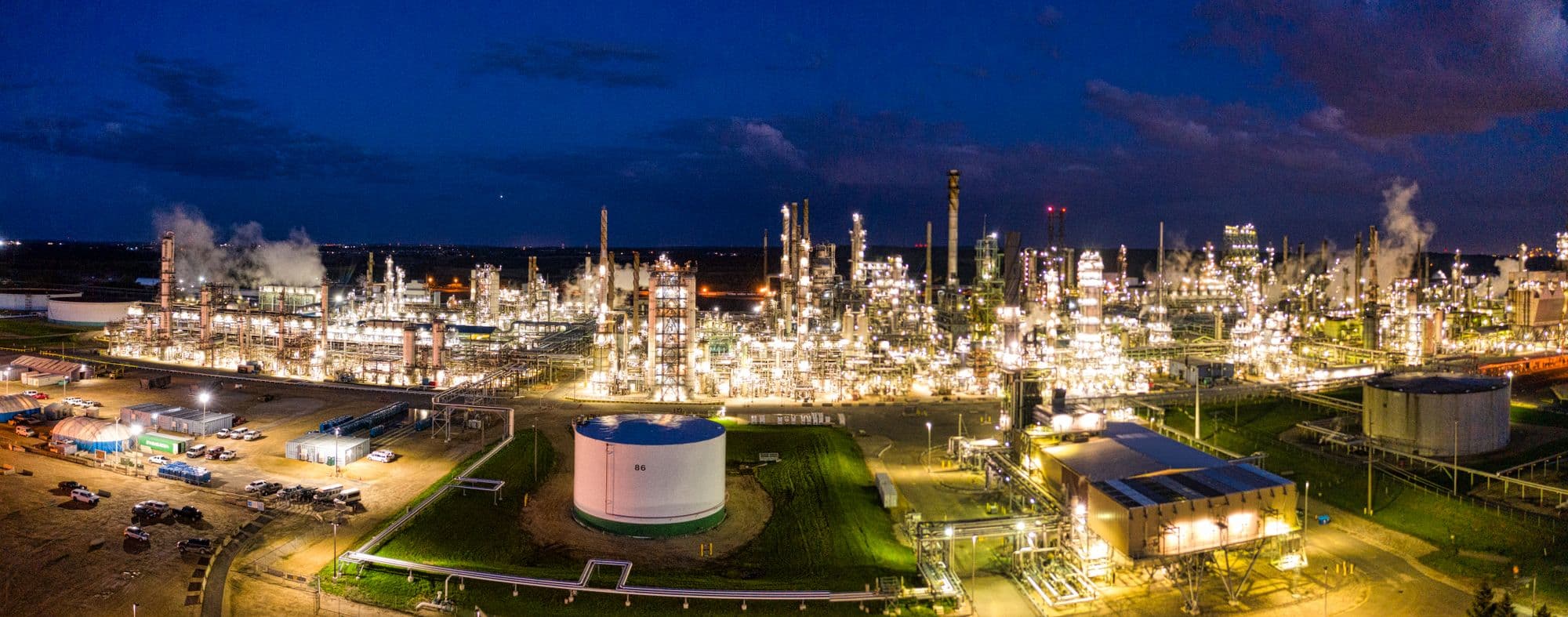 Aerial view of a lit refinery and tank farm at night