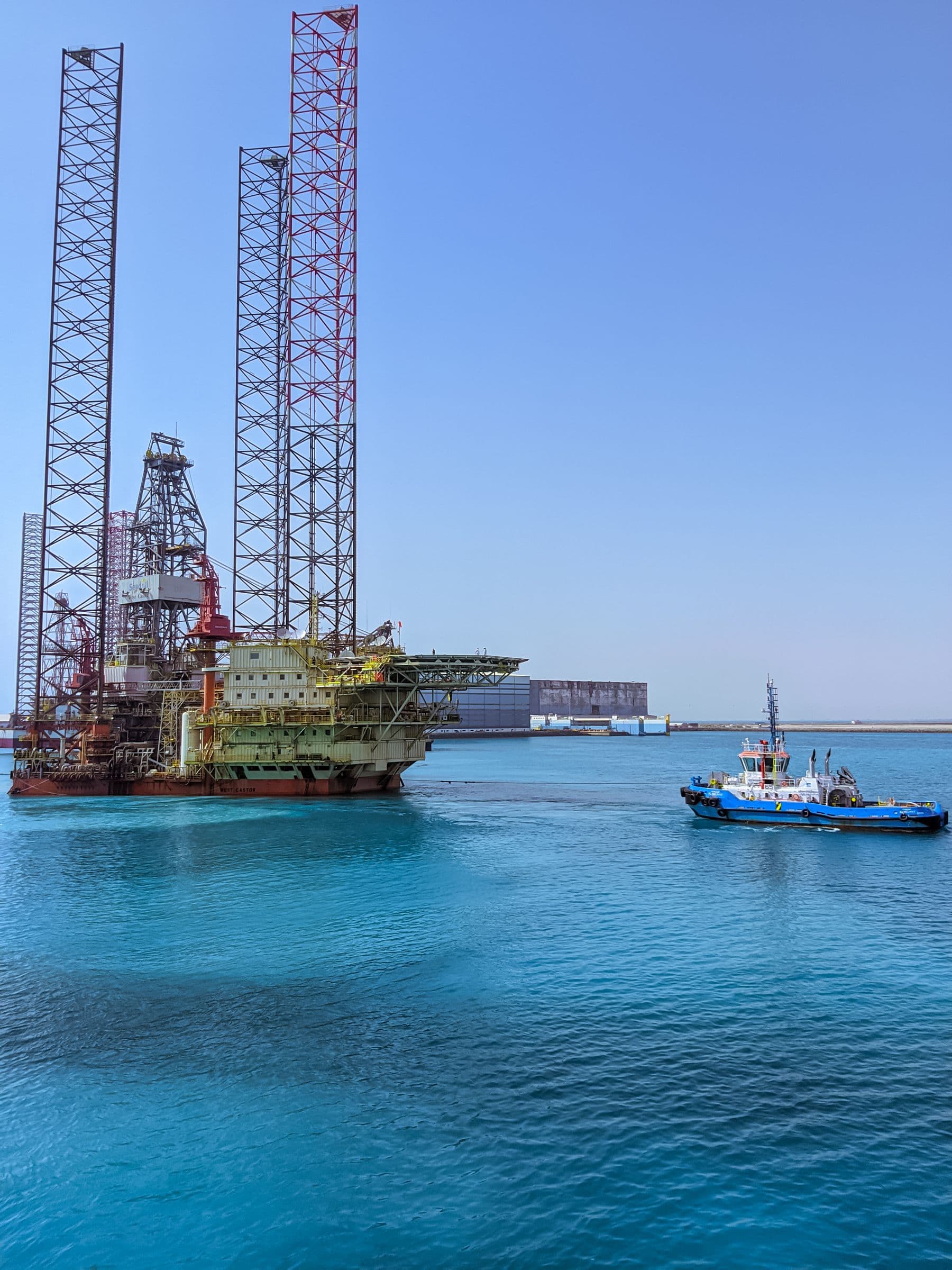 Offshore rig with a tug alongside in a working harbour