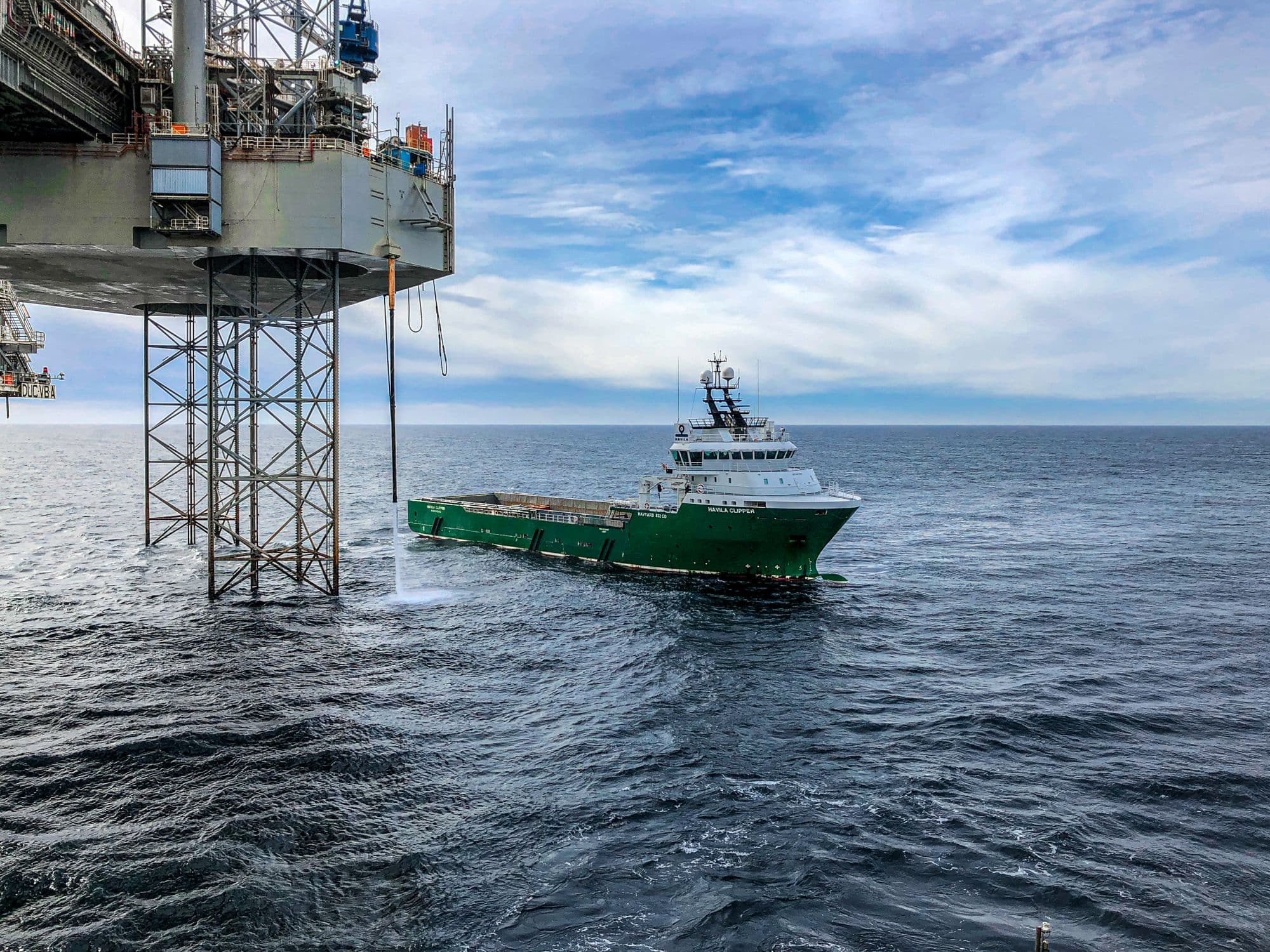 Offshore supply vessel working alongside a fixed production platform in open sea