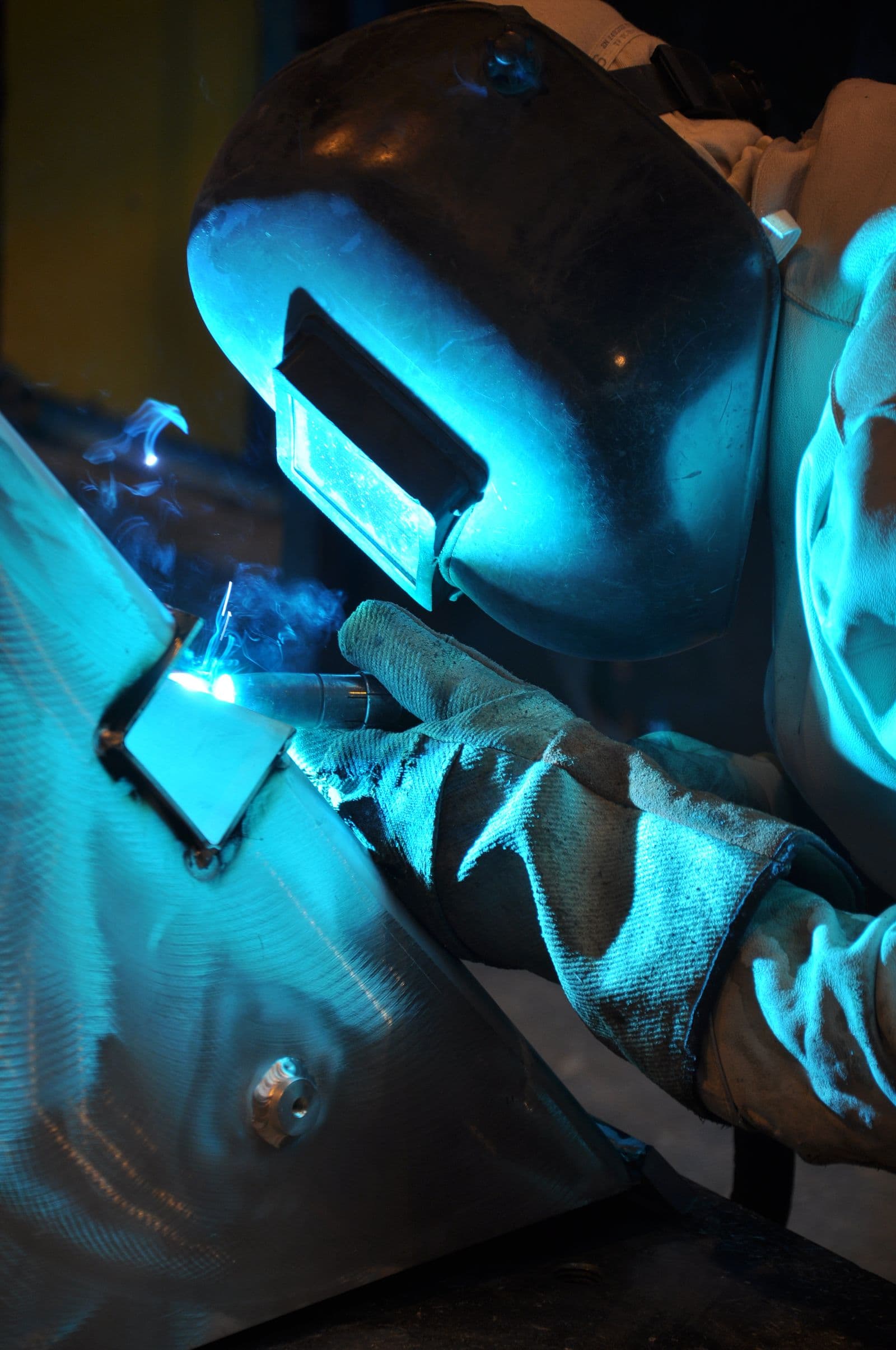 Welder in protective gear joining steel in a workshop