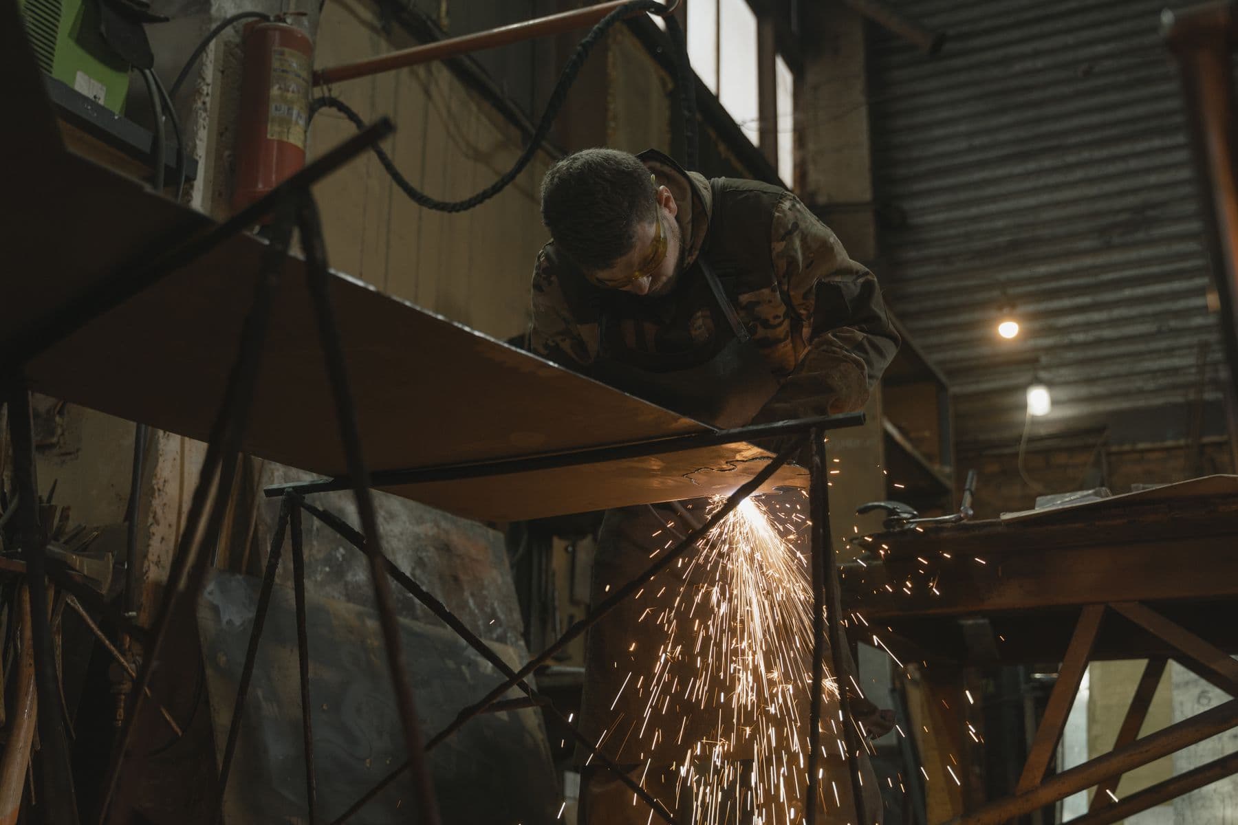 Welder joining steel sections in a fabrication workshop, sparks visible